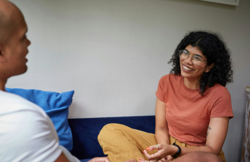 Photo of two people sitting adjacent across from each other, seemingly in conversation