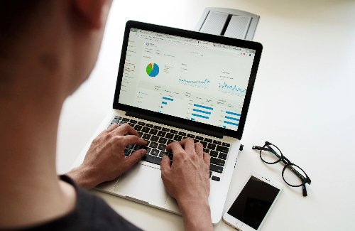 Person typing on computer which displays multiple graphs 
