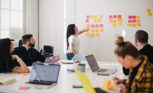 A woman places sticky notes on a whiteboard. 