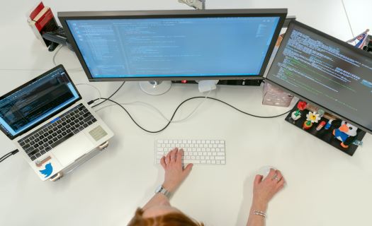A person working on multiple computers at their desk.