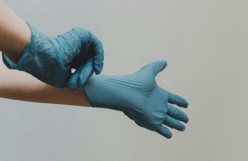 Pair of hands putting on a pair of medical gloves