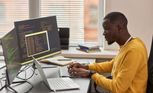 man sitting at desk typing on computer