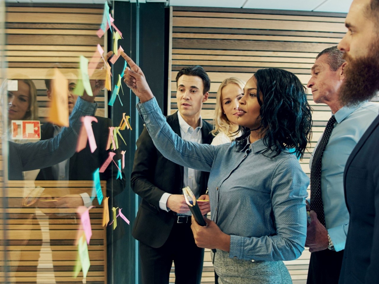 Five people meeting around a sticky note board