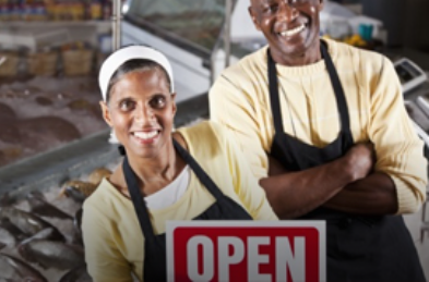 Shop owners with opening sign