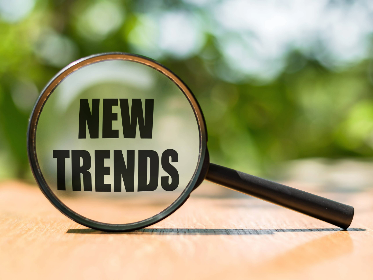 Magnifying glass positioned on its side with words New Trends centered in the lens