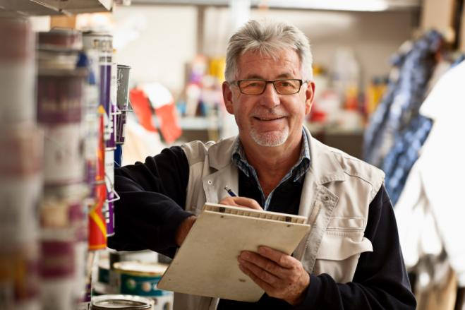 Older worker in warehouse smiling