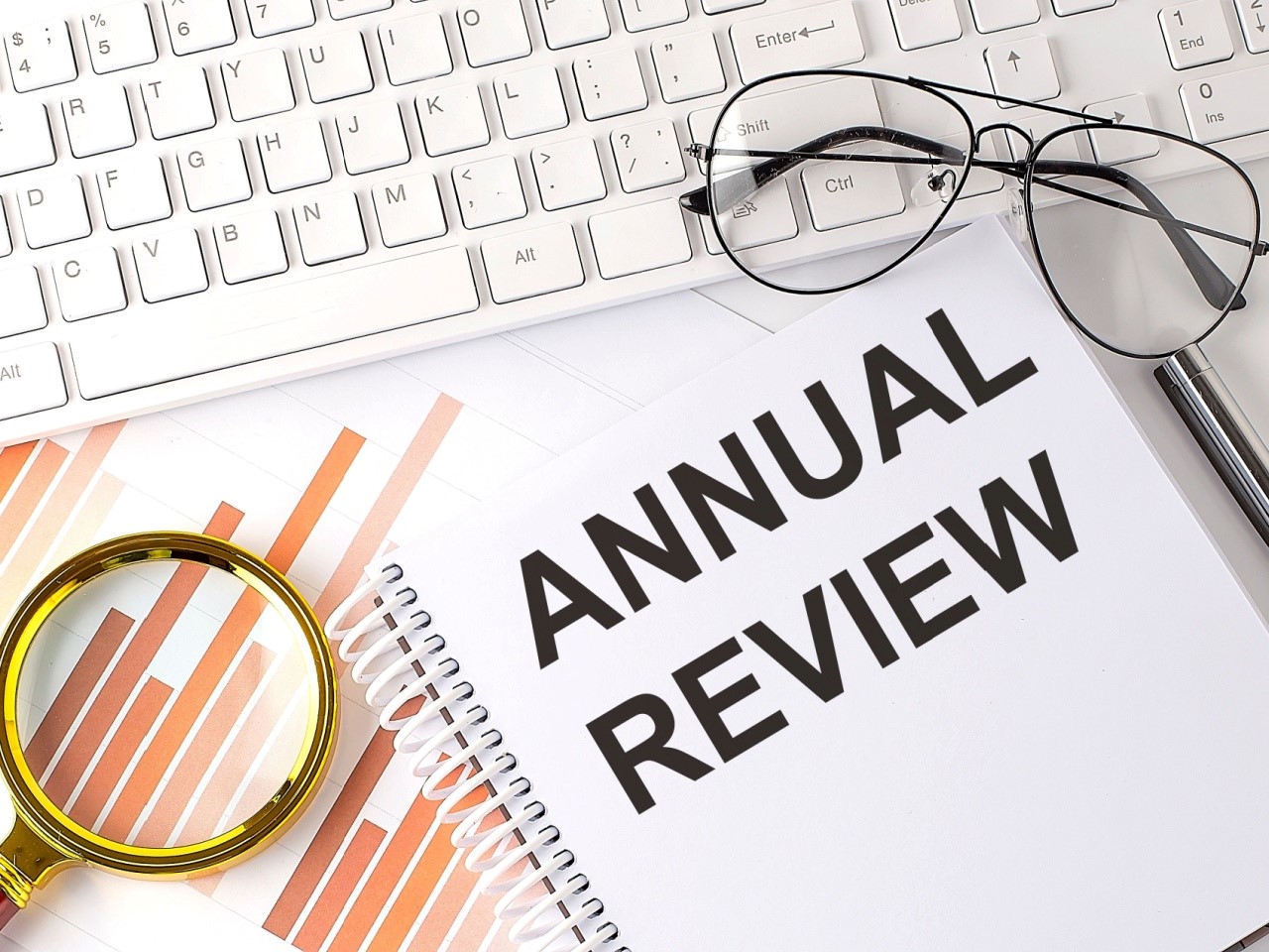 Keyboard, glasses, graphs, and a notebook with the words Annual Review.