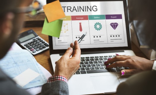 African-American man and woman looking at laptop with postit notes attached and the word "training" on the screen