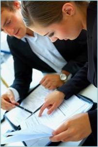 A woman and a man reading over paper work laid out on a table or desk