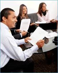 a man and two women sitting around a table holding papers