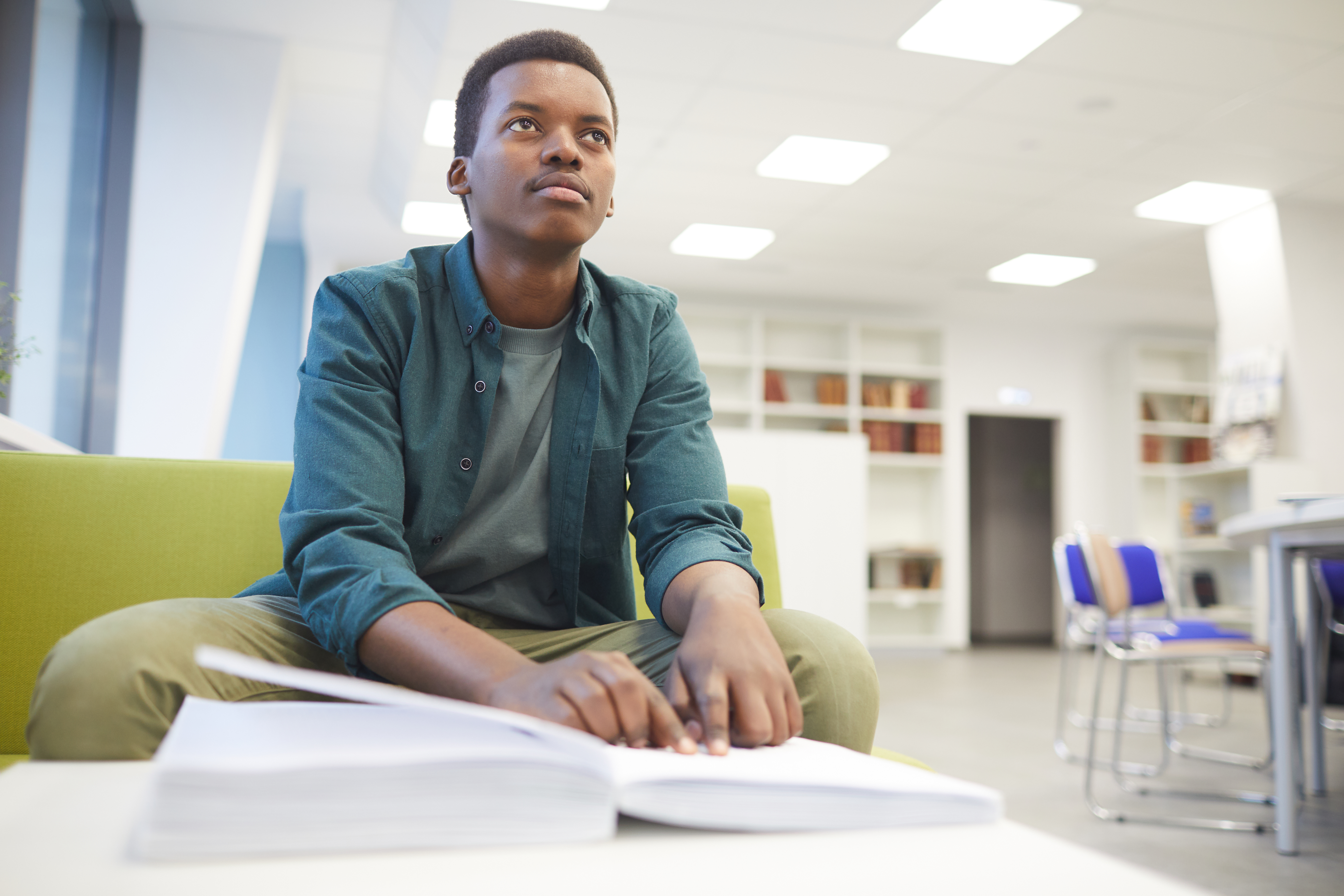 Young man reading braille in a library