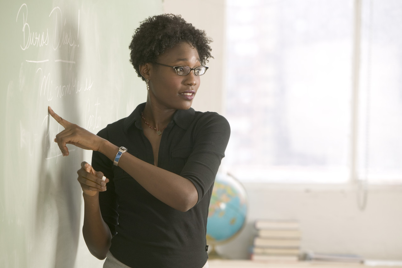 Female African American teacher pointing at chalkboard