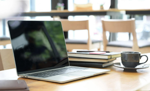 Laptop on a desk with books and coffee