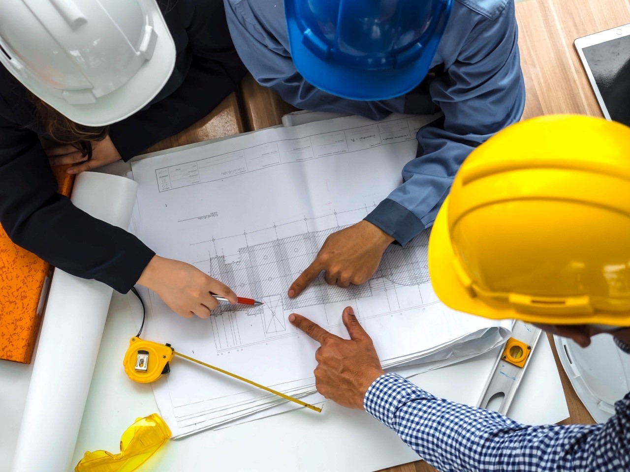 Civil engineers in hard hats pointing at a schematic