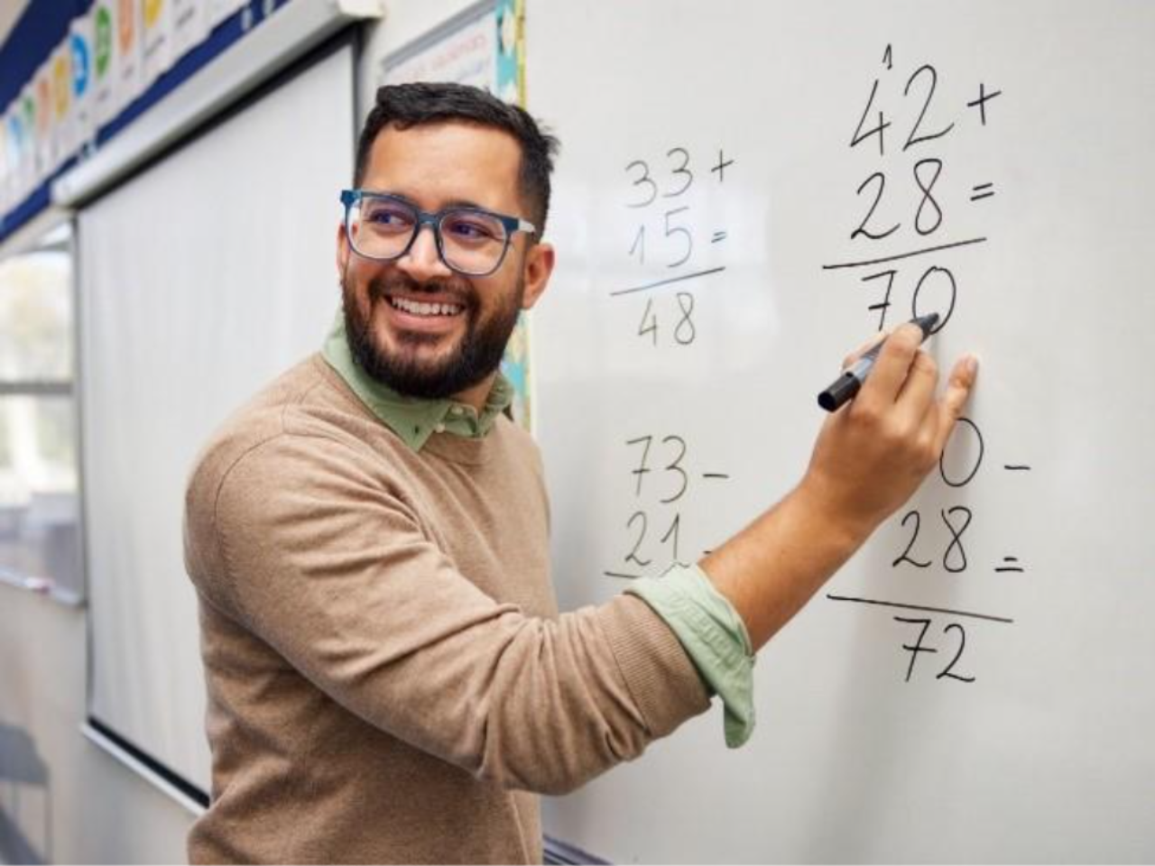 Teacher smiles while writing math equations on a white board