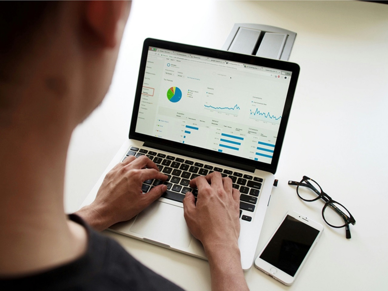 White man typing on laptop with financial display