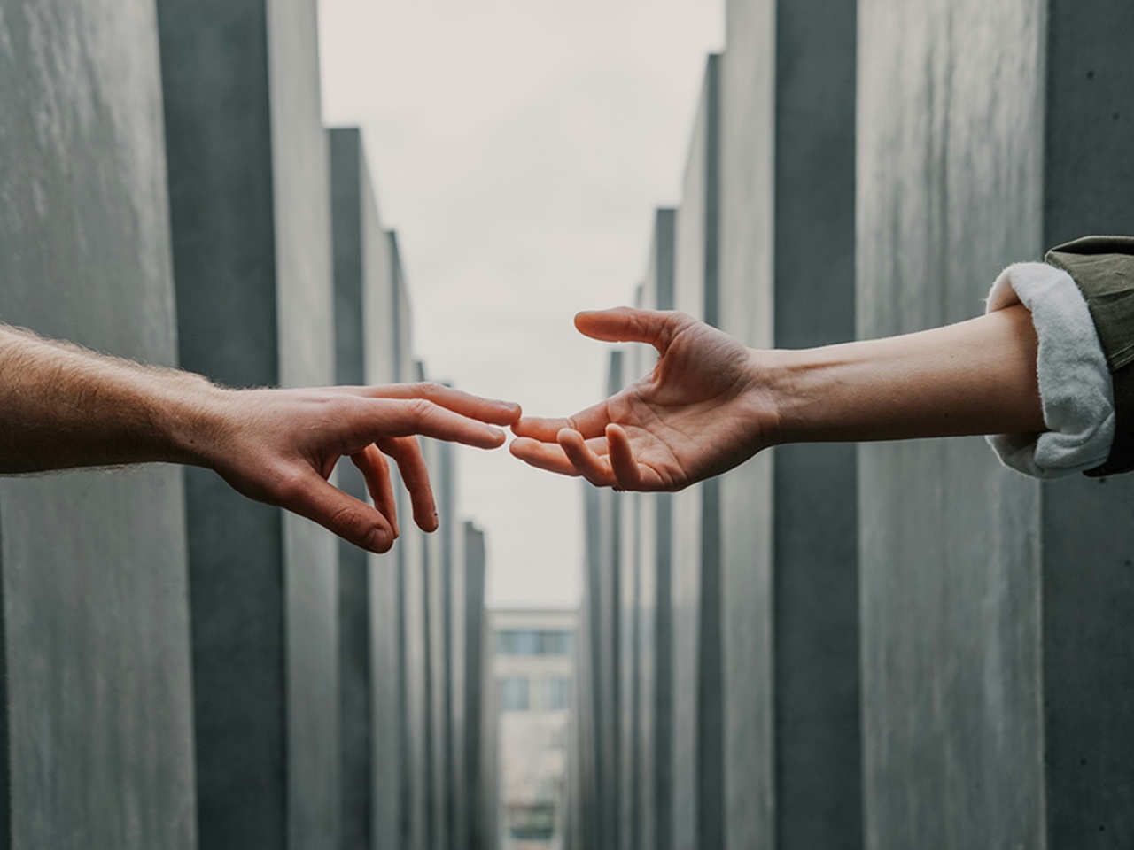 Two hands reach across a gap to touch