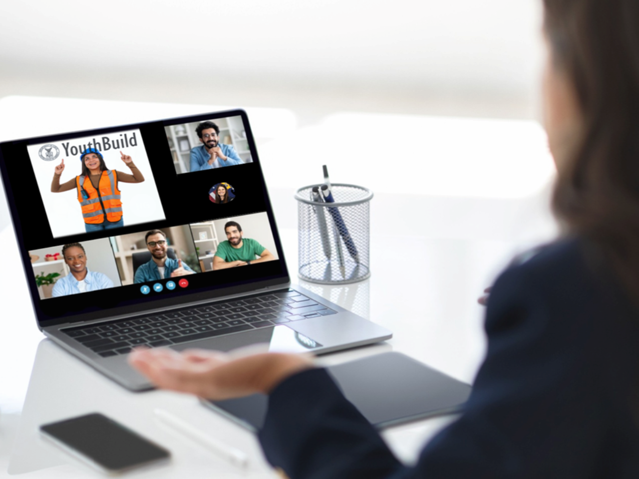Woman attends virtual meeting on computer which features YouthBuild logo