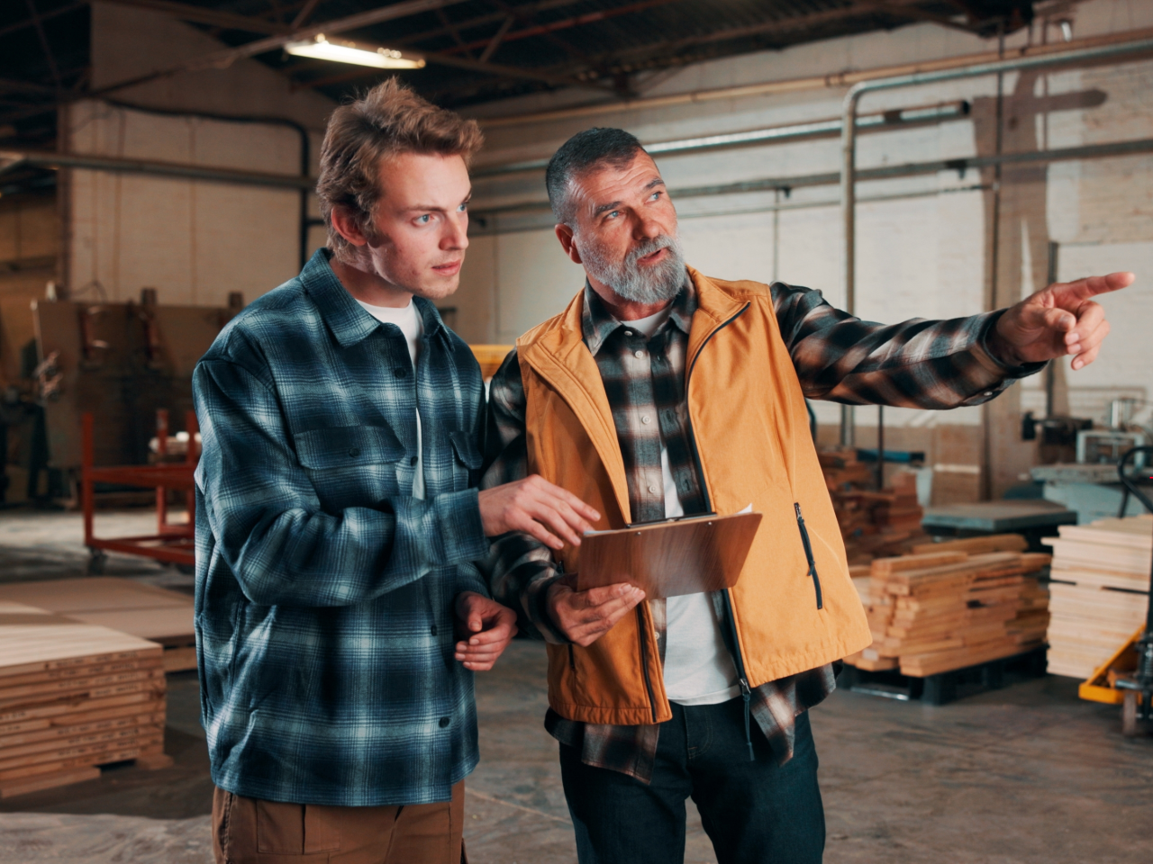 Worker points to the distance as he and another man look at a clipboard