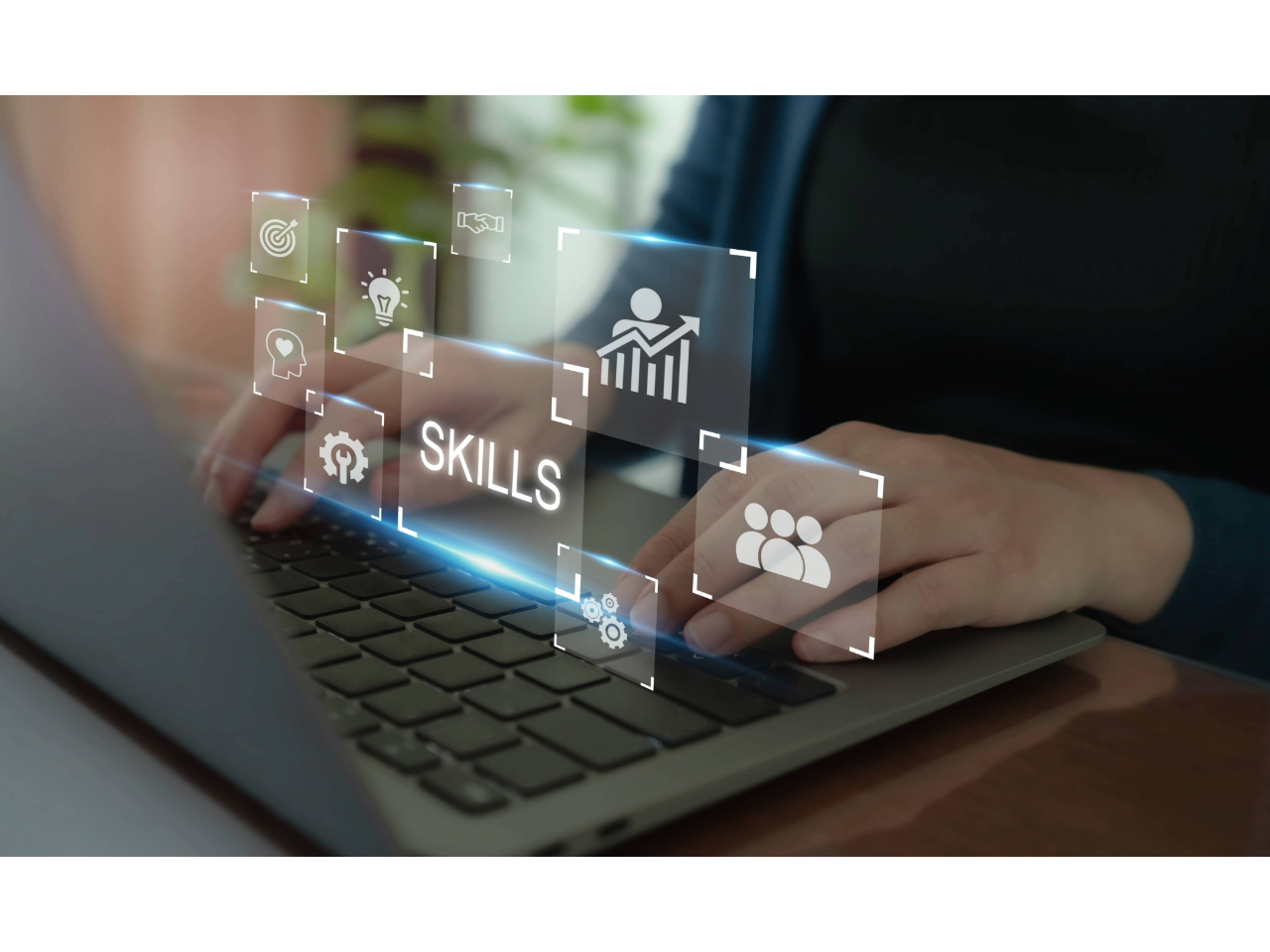 Hands typing at laptop with the word skills hovering above the laptop keys in a transparent window