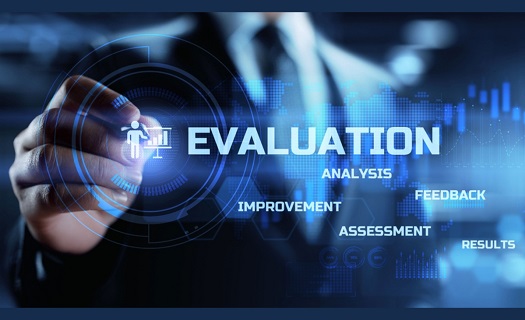 Person in a business suit using a stylus to click on a transparent touchscreen displaying words like EVALUATION,  ANALYSIS, IMPROVEMENT, FEEDBACK, ASSESSMENT, RESULTS