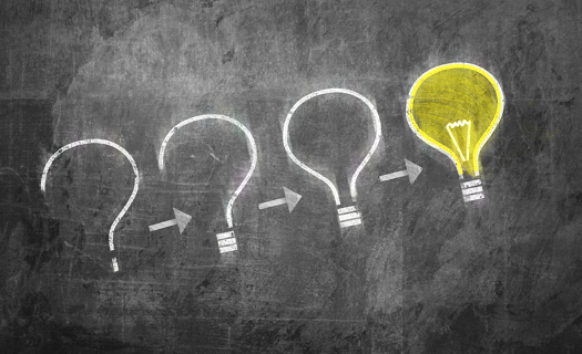 Chalkboard with series of question marks that turn into a light bulb.