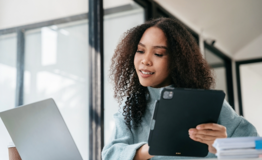 Young female entrepreneur works at a laptop and tablet in a modern office.