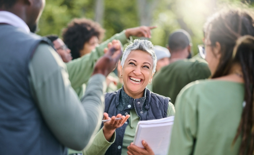 Woman with short gray hair speaking outdoors with a group of colleagues.
