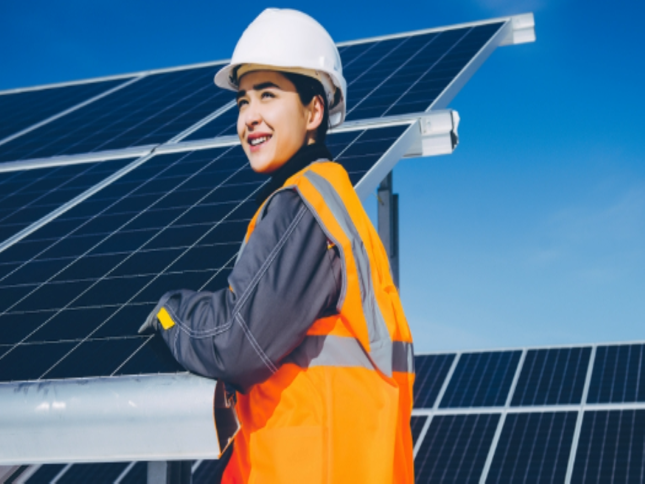 A worker installing solar panels on a sunny day.