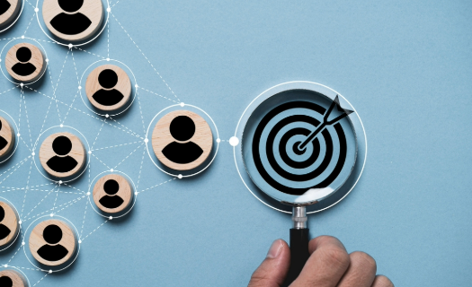 Magnifying glass displaying an arrow hitting a target and a group of silhouettes representing a target audience.