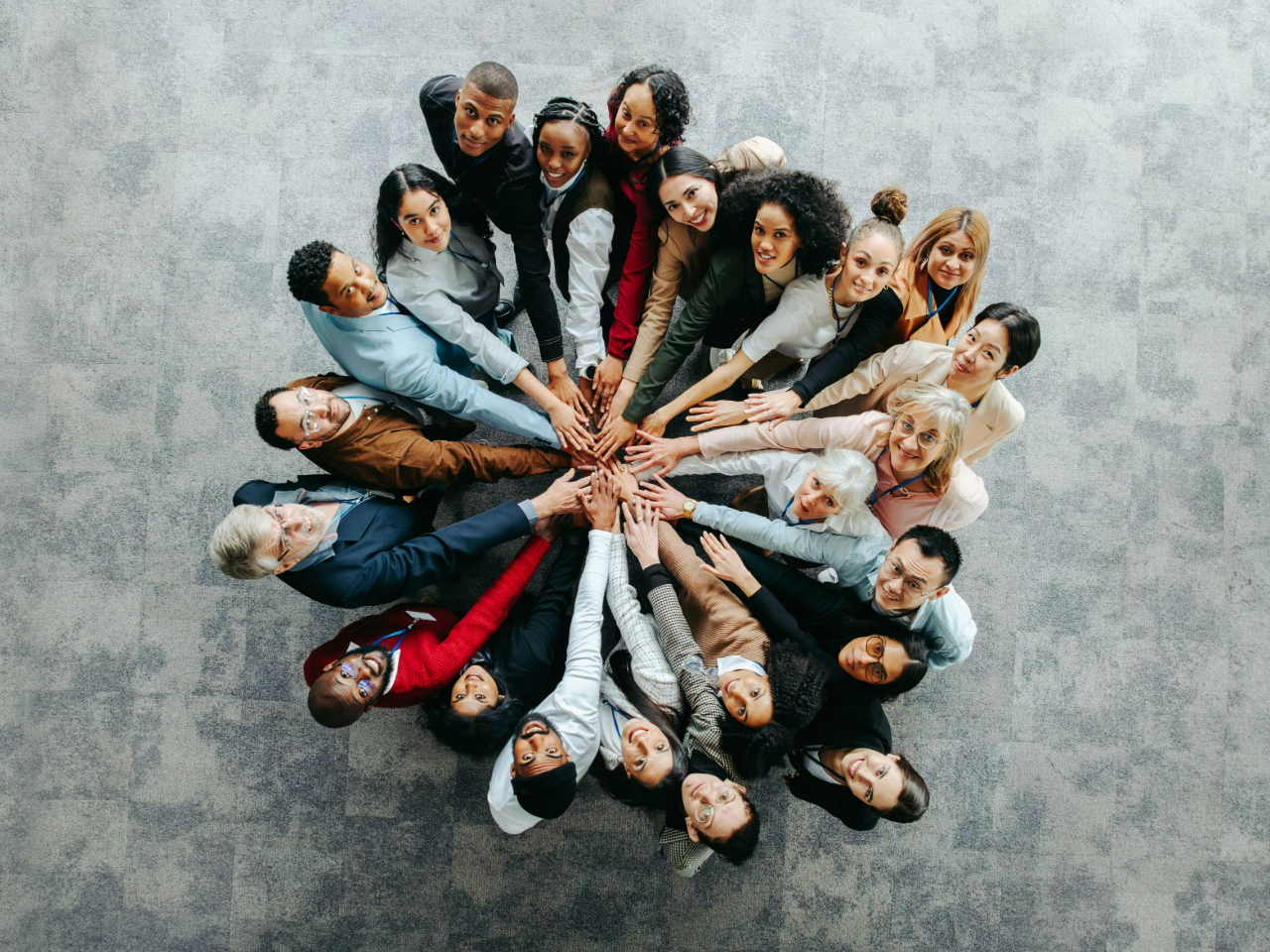 A group of diverse professionals with their hands stacked in the center for a team huddle.