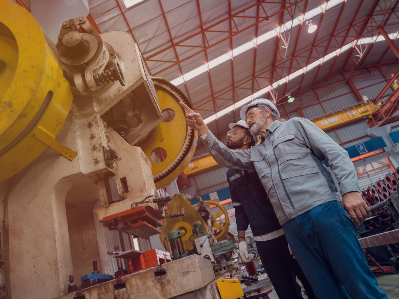men with hard hats look up at machines