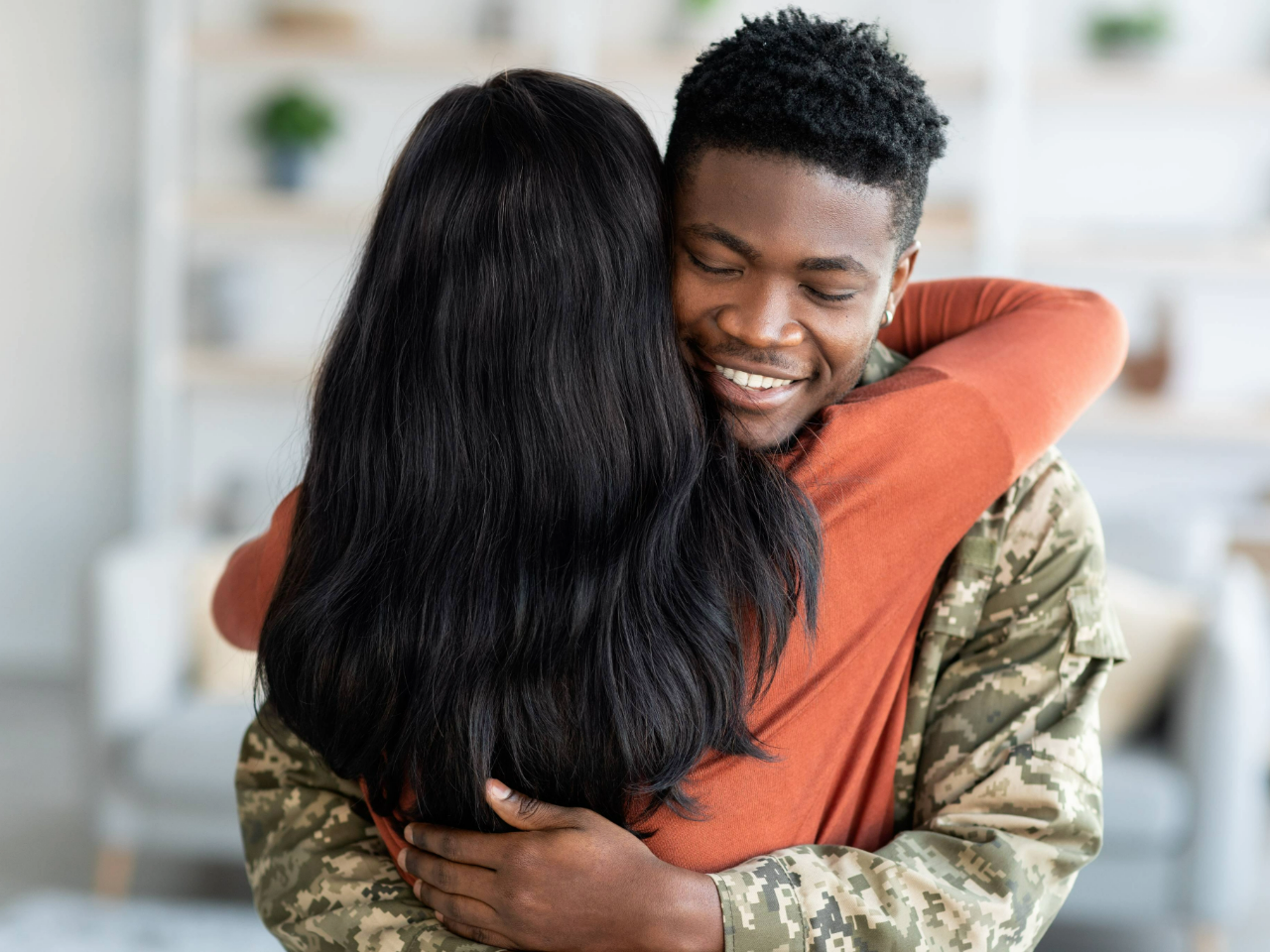 A soldier in uniform embraces his partner.