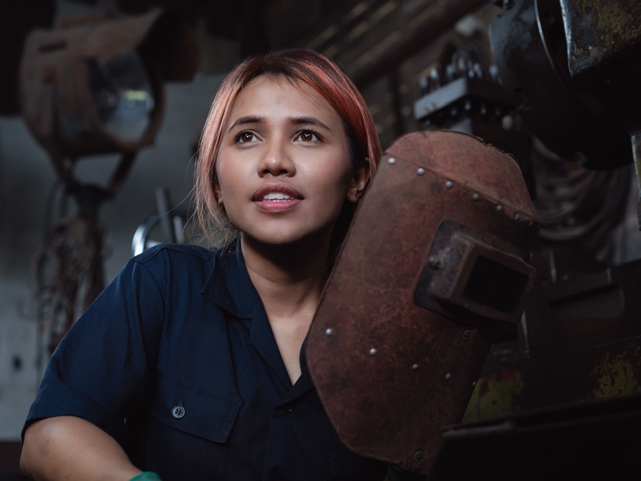 Young woman removes welding mask